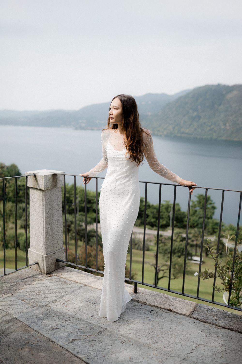 Sposa appoggiata alla ringhiera di una terrazza sul lago