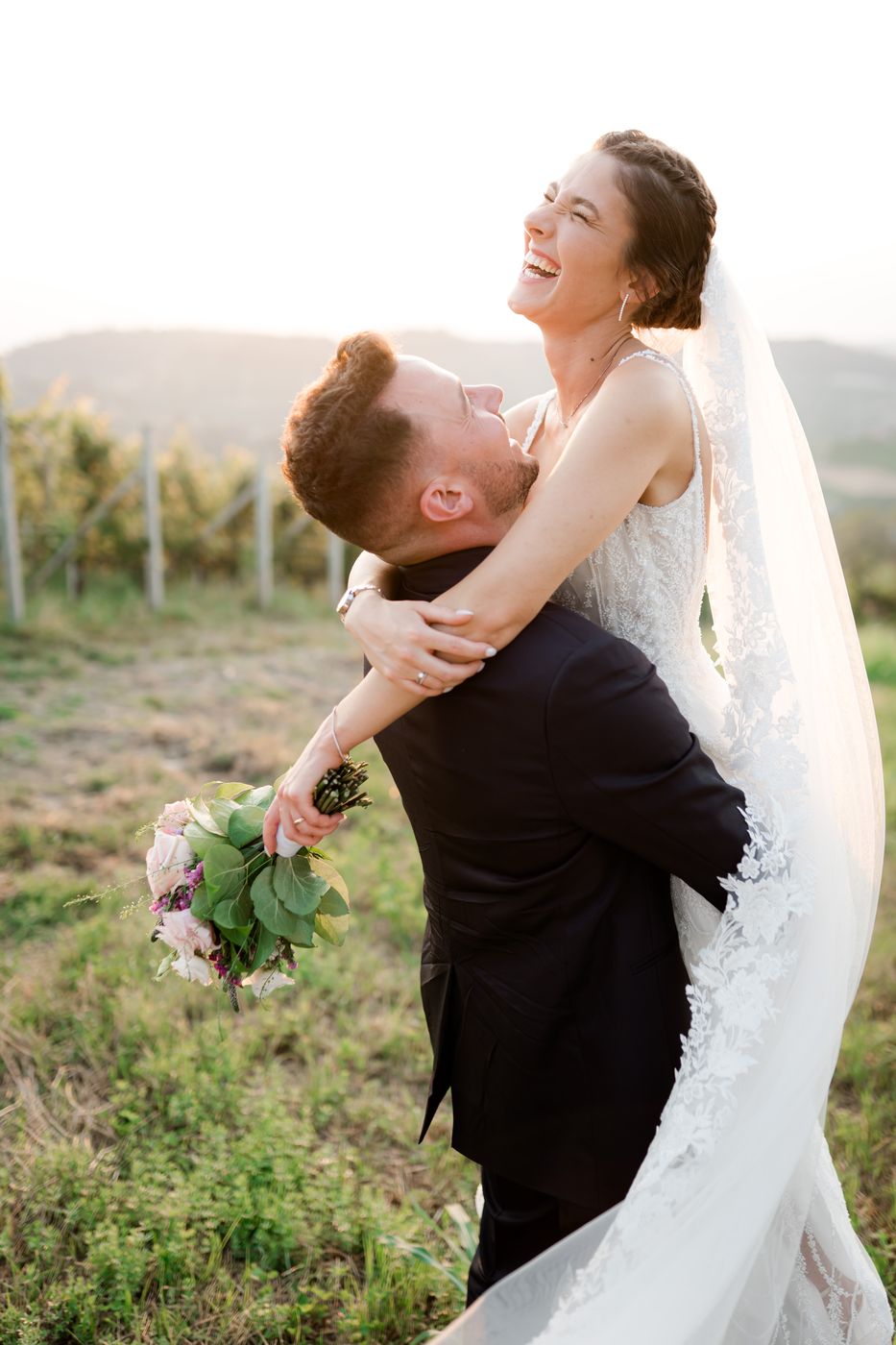 Lo sposo solleva la sposa in un prato tra le vigne